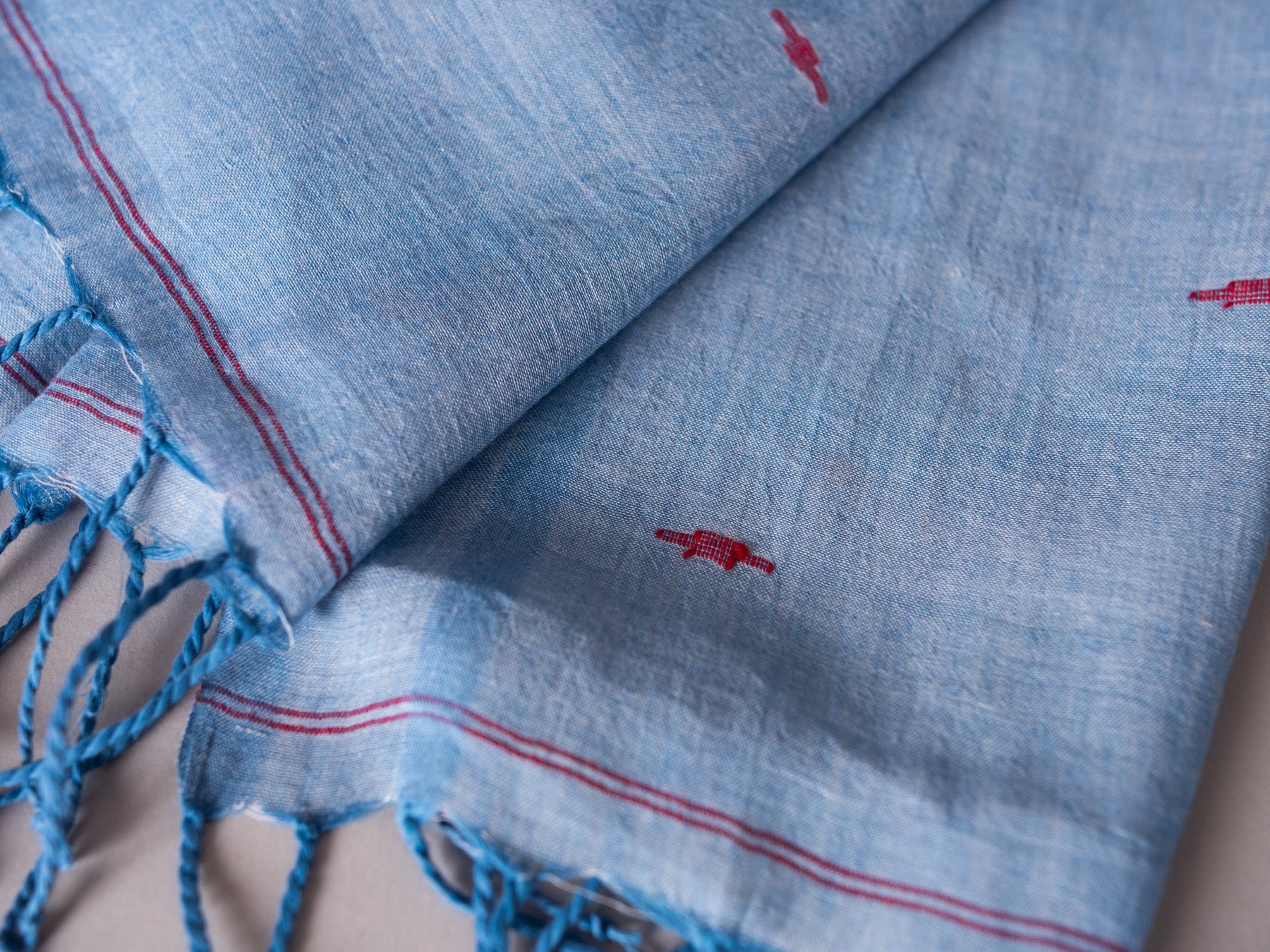 Hand loomed fine cotton jamdani in blue with red motifs.