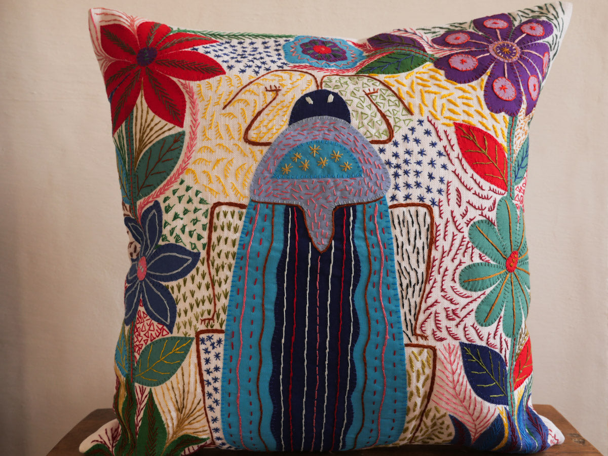 Coussin brode main avec des motifs insectes et fleur, commerce equitable. Main image