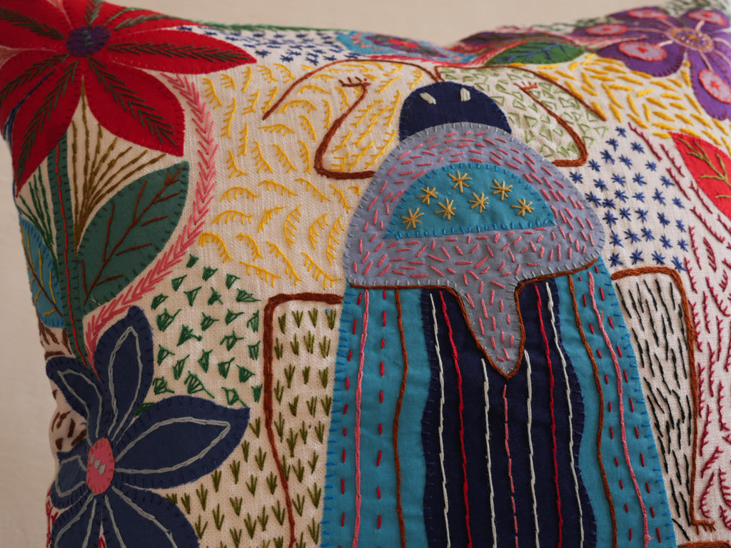 Coussin brode main avec des motifs insectes et fleur, commerce equitable.