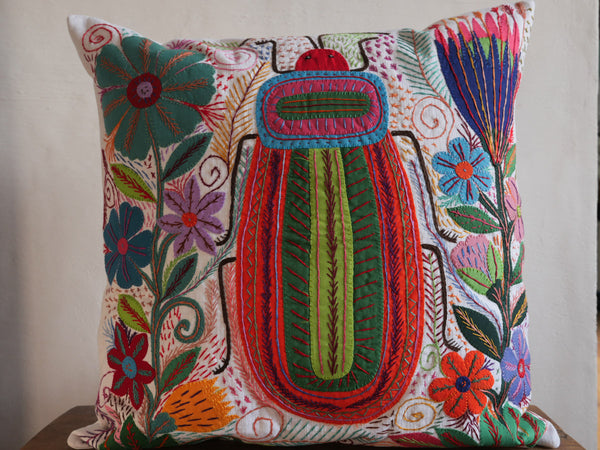 Coussin brode main avec des motifs insectes et fleur, commerce equitable.