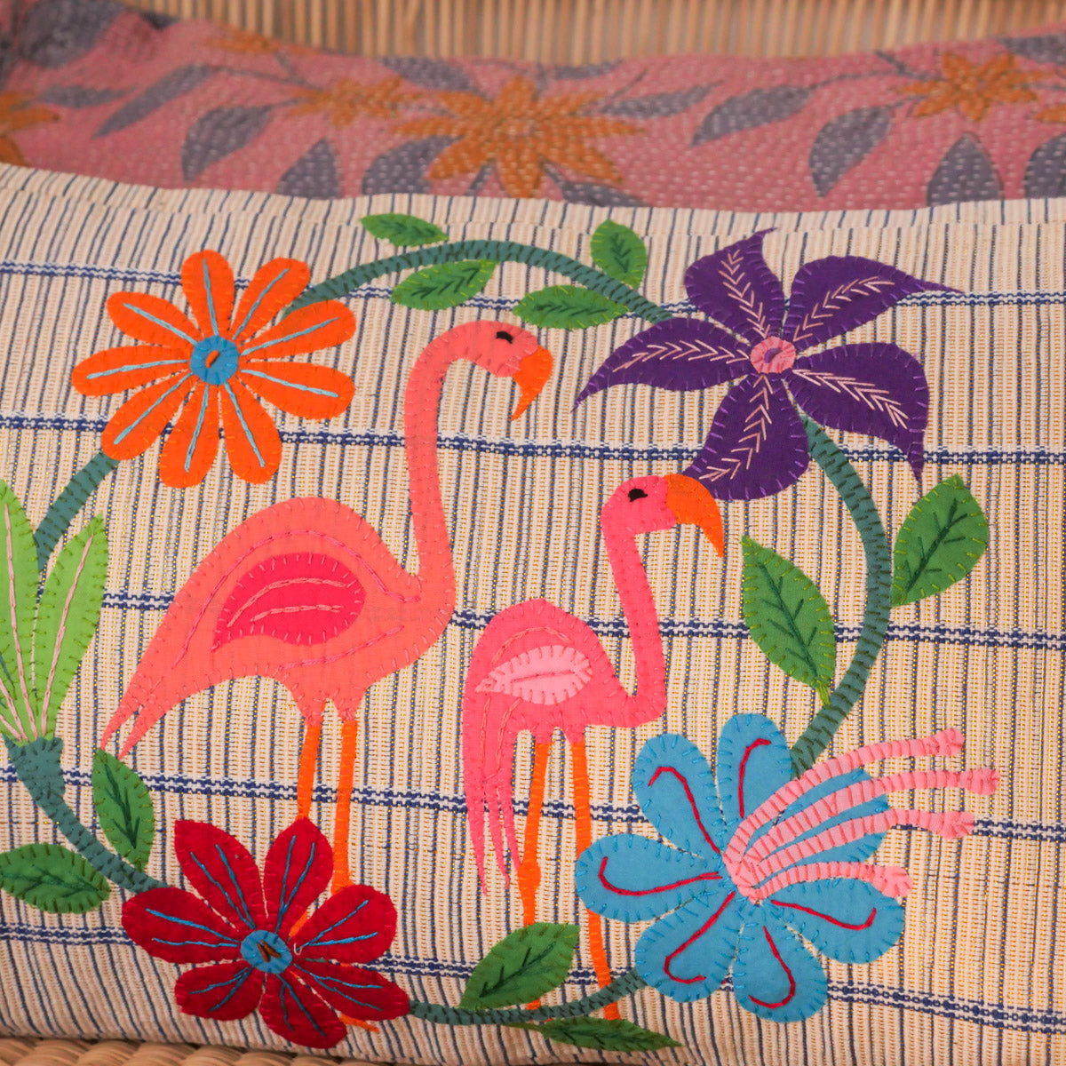 A unique collage of flamingos and flowers, in appliqué and embroidery on a hand loomed cotton cushion